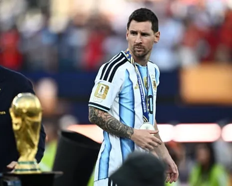 Lionel Messi walks past the World Cup trophy